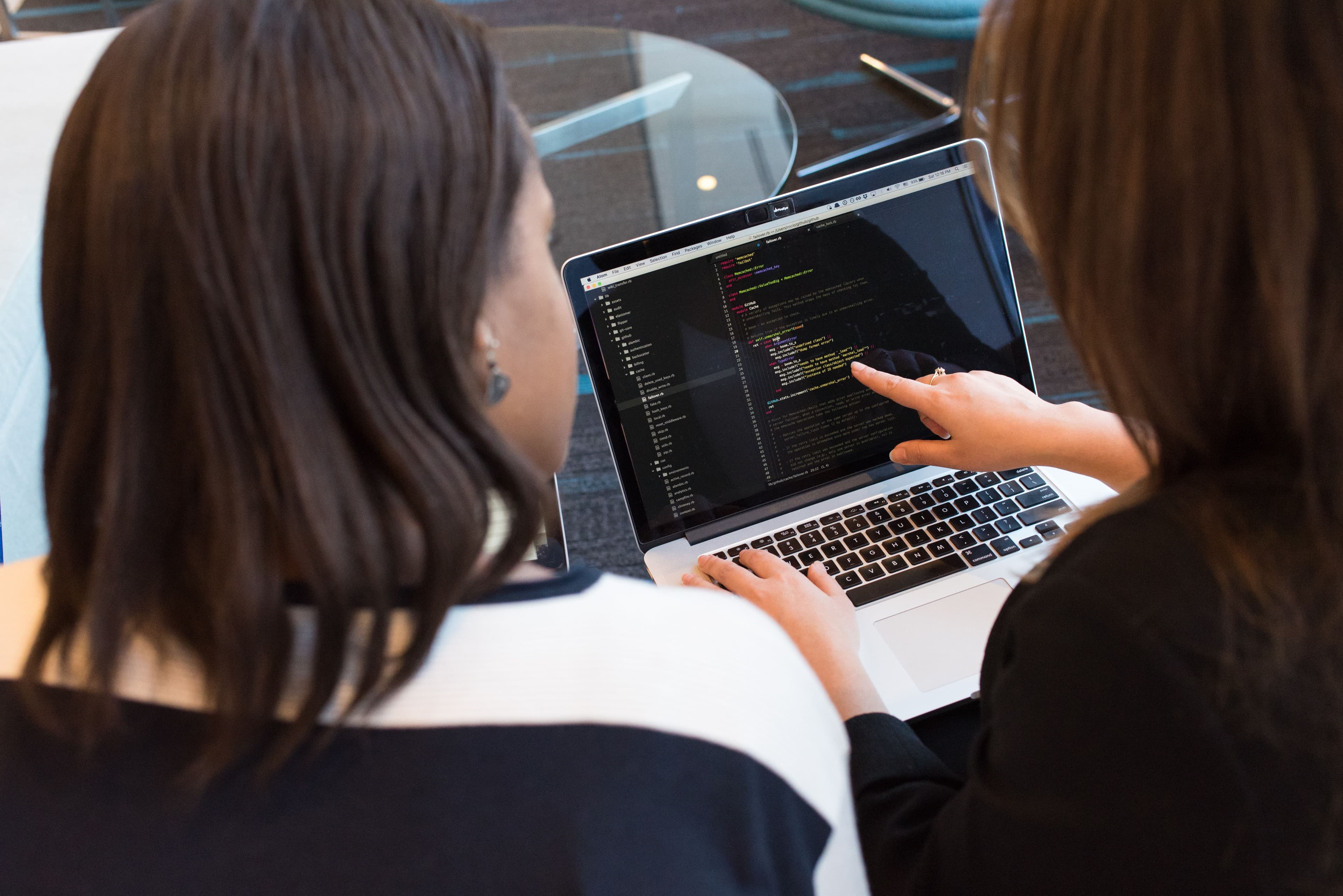 Dos mujeres revisando código juntas en una laptop
